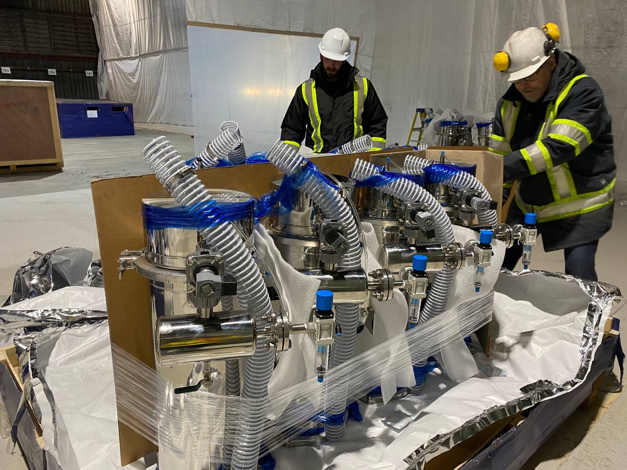 Technicians unpacking stainless process equipment on a plant floor