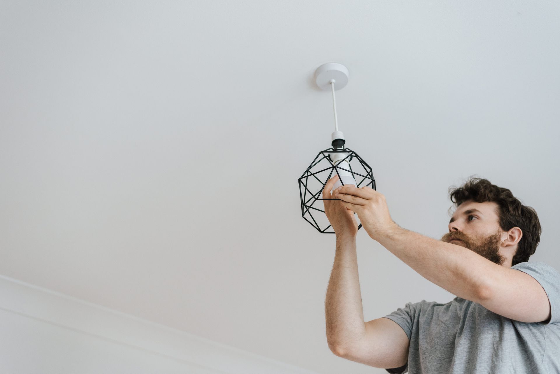 Electrician installing a ceiling light fixture in a home