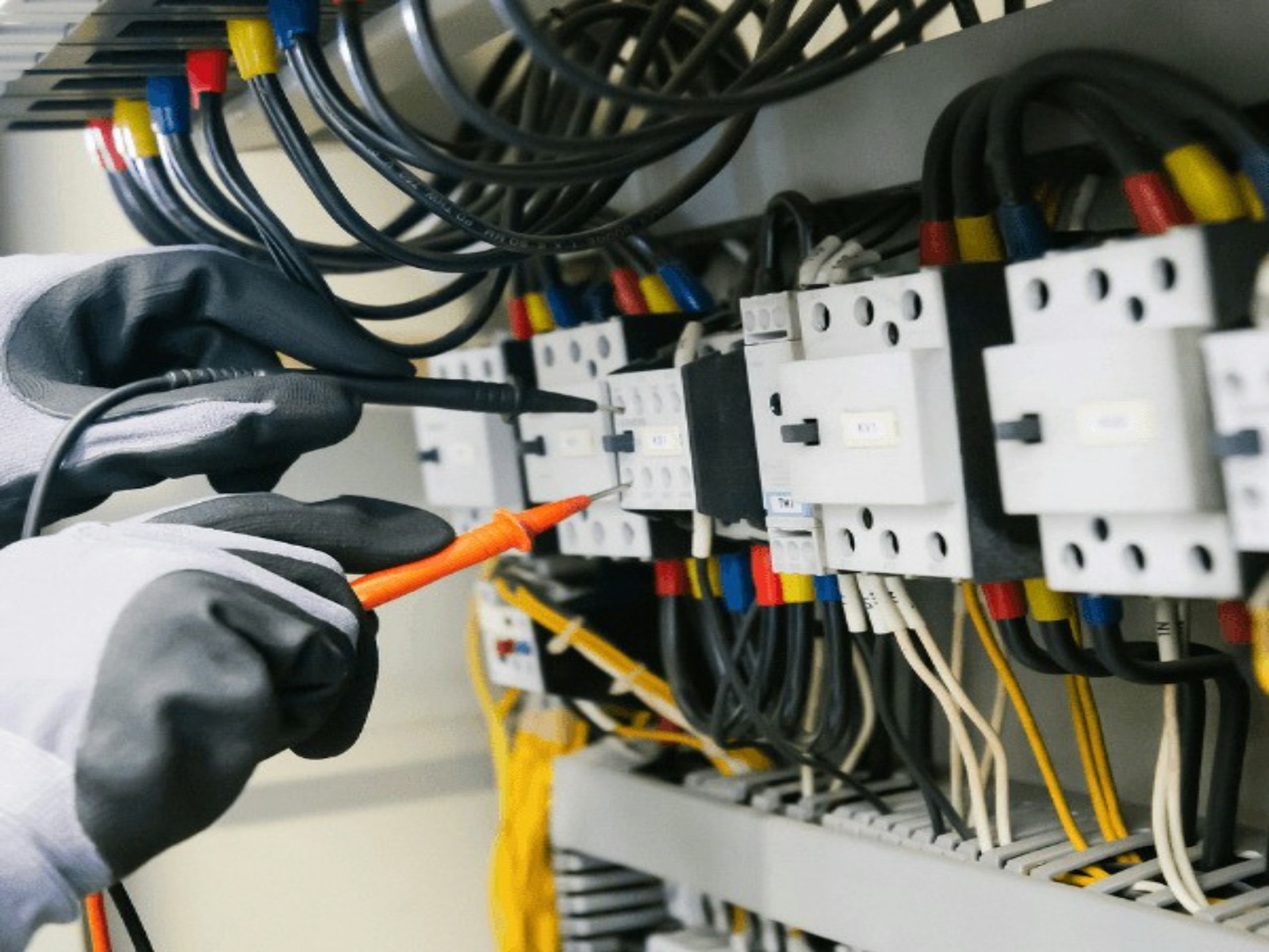 Electrician testing control panel contactors in a commercial building